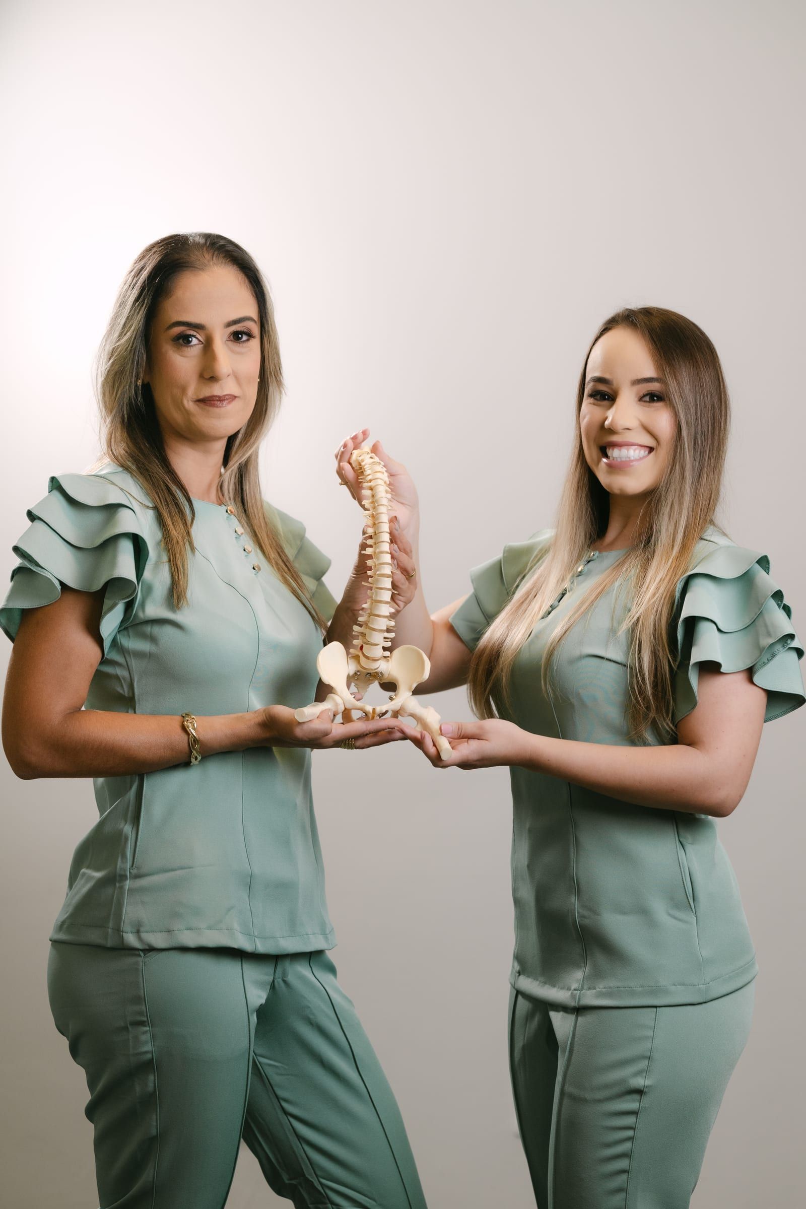 Fisioterapeutas da Movita segurando um modelo anatômico da coluna vertebral